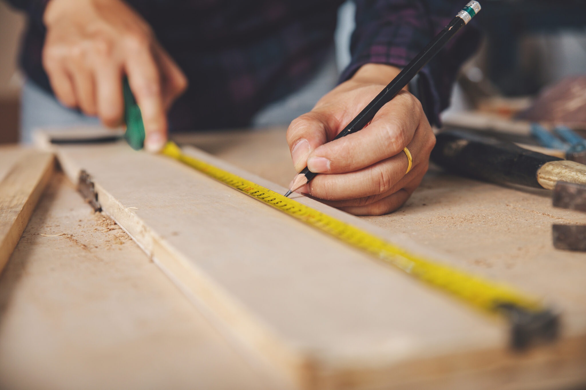 carpenter with a pencil and tape measure mark on wooden board on